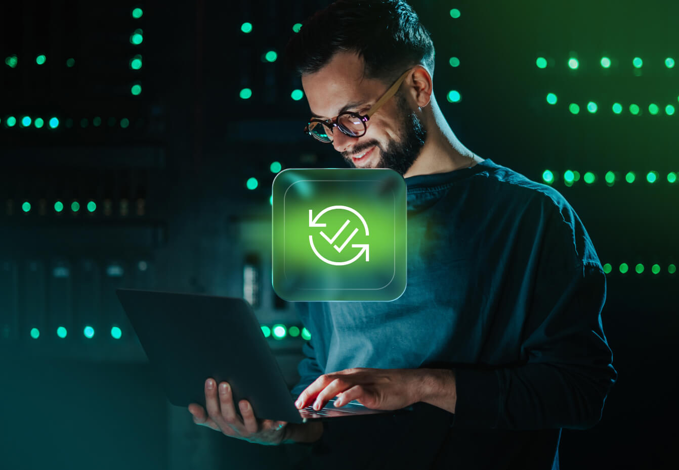 Bearded man in glasses uses a laptop in a server room with green lights, overlaid with a continuous monitoring icon.