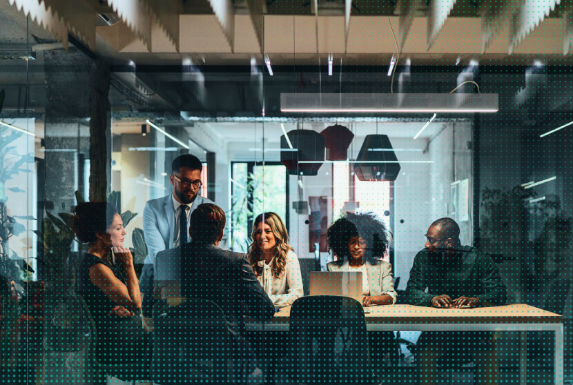 Diverse business team collaborating around a conference table in a modern office, viewed through glass with dot overlay.