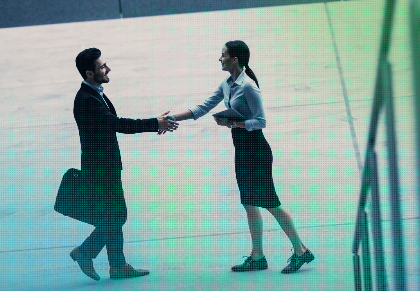 Businessman with briefcase shaking hands with businesswoman holding a tablet in a modern office setting.