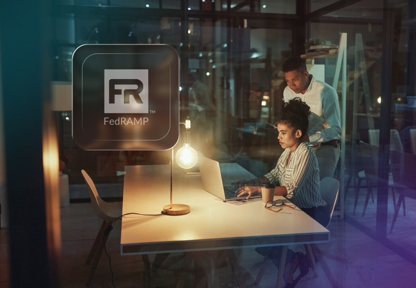 Two colleagues collaborate at a laptop in a dimly lit office beside a FedRAMP logo icon and glowing lamp.