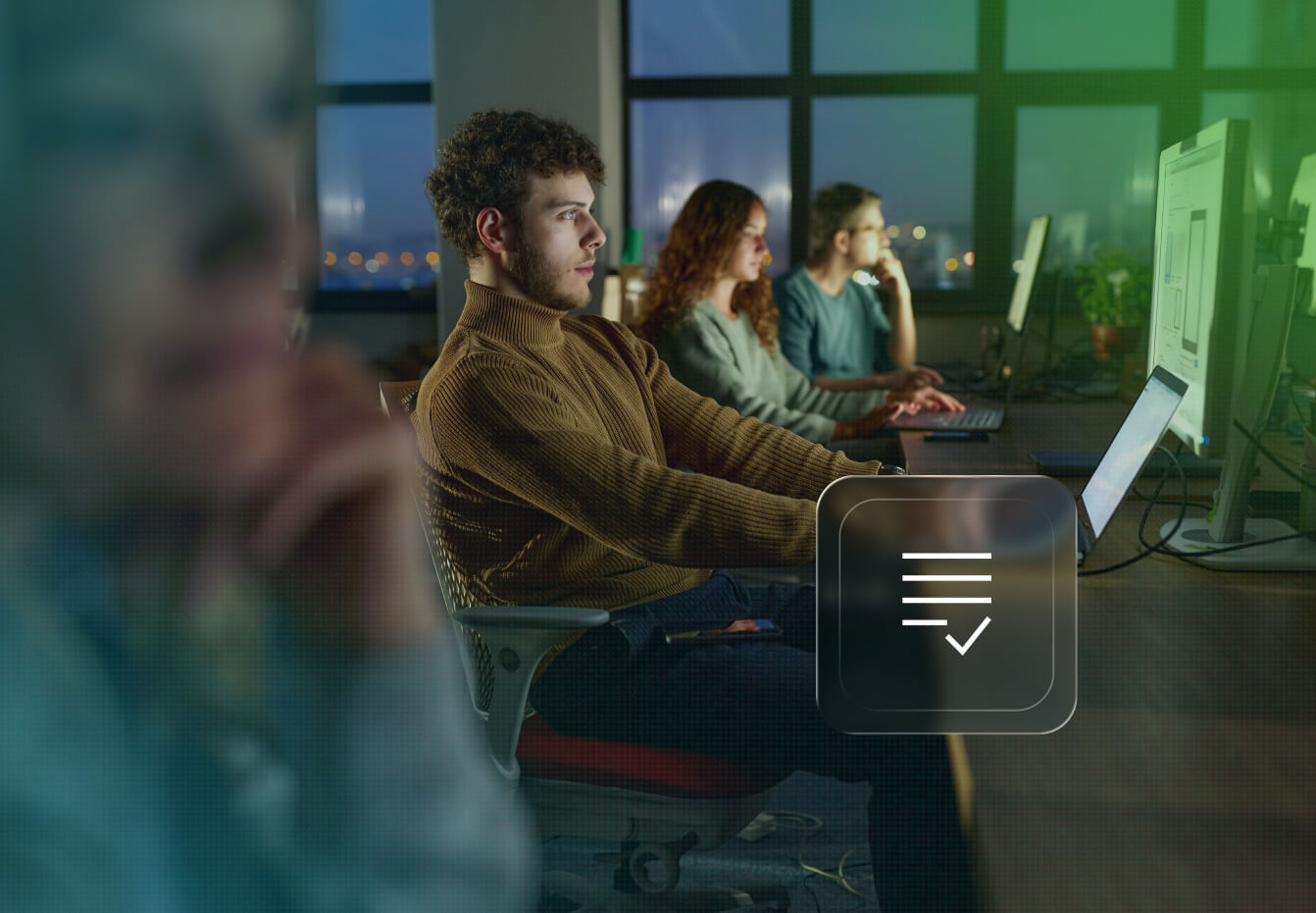 Team members working at computers in a modern office at night with a compliance checklist icon overlay.